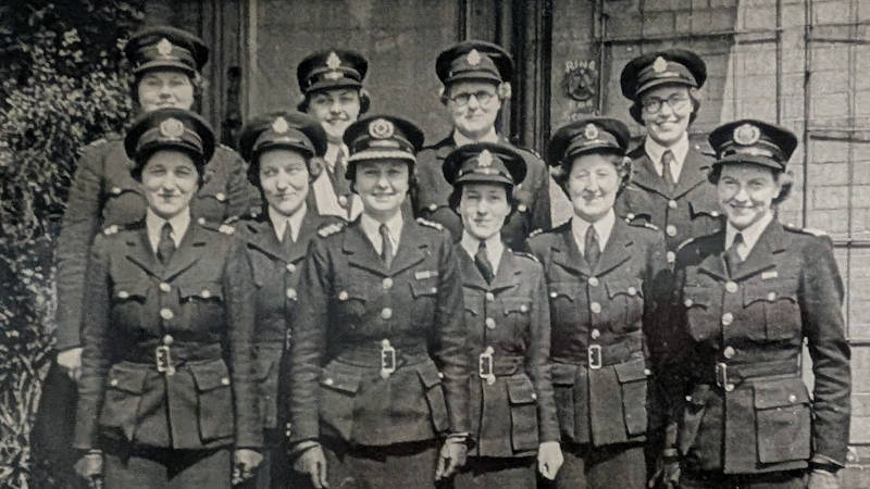 A group of uniformed people standing together in rows outdoors, posing for a formal photograph.