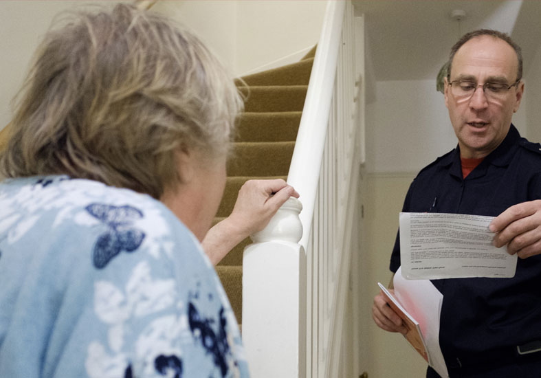 Firefighter  reading from a piece of paper to community member 