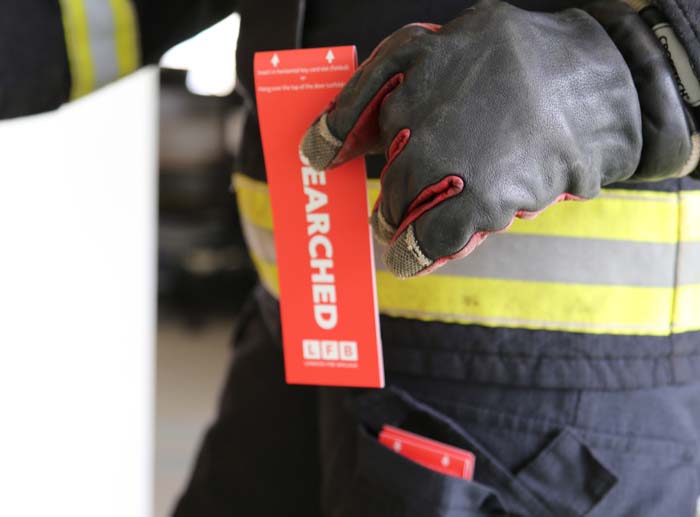 Red searched tag in a firefighters gloved hand