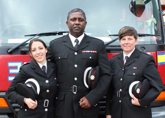 3 Firefighters stood in front of red fire engine 