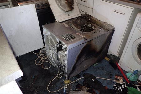 Fire damaged tumble dryer on a kitchen floor