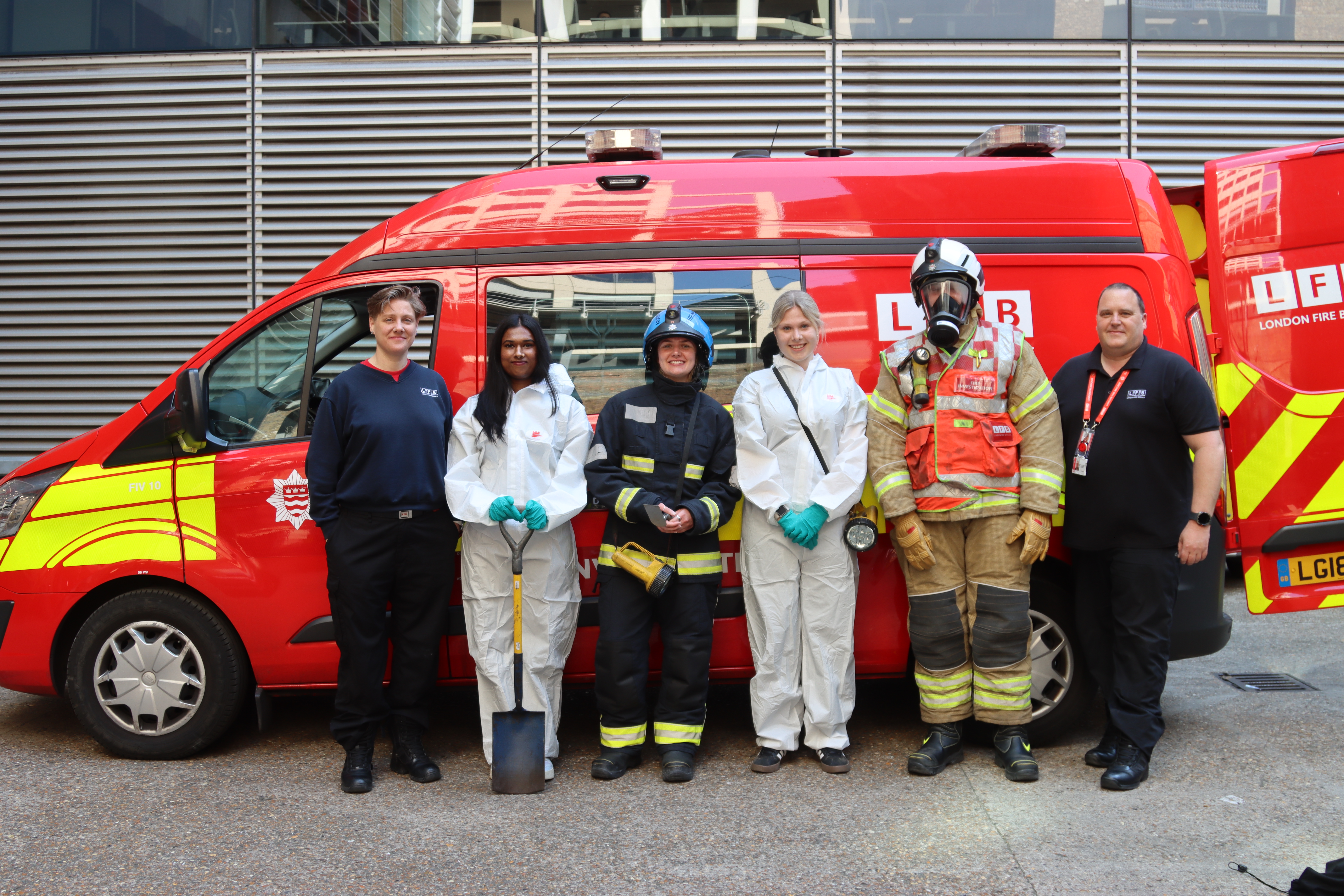 Students from University of Greenwich wearing fire investigation PPE with fire investigators in front of fire investigation van