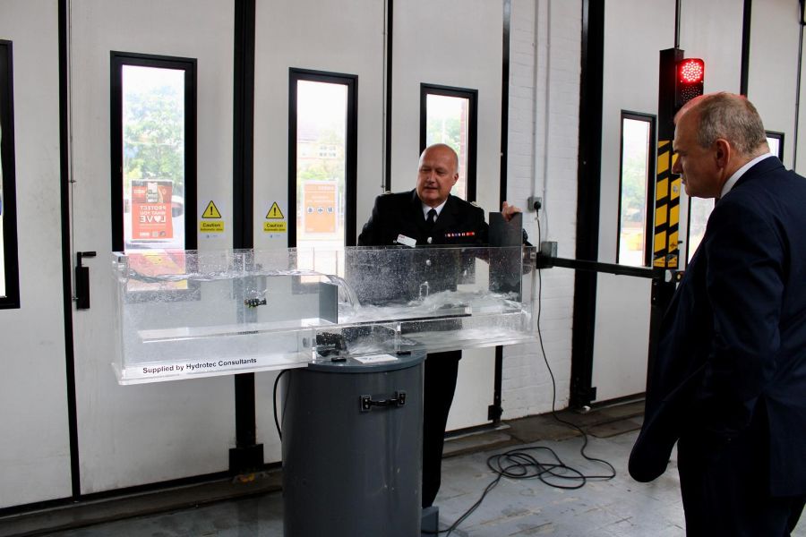 Borough Commander Rob Davies demonstrating the river flume tank in an appliance bay while Sir Ed Davey watches