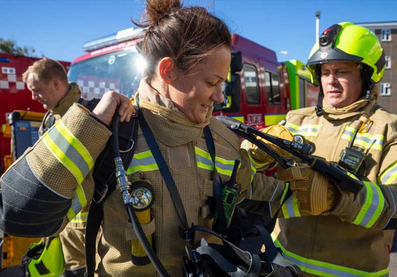 Firefighter getting breathing apparatus on her back
