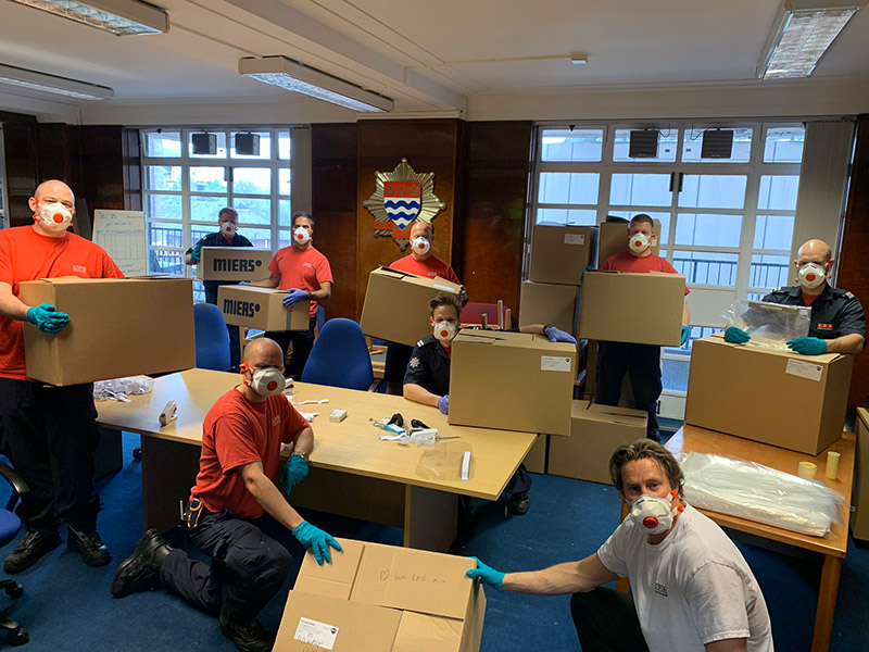 Firefighters wearing face masks with packages for delivery
