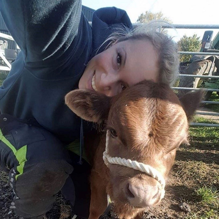 Firefighter Emily Butler pictures with a calf on her family farm