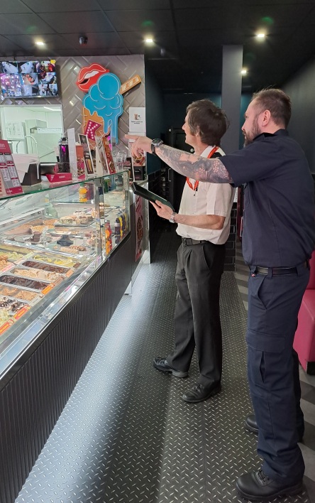 Firefighter and inspecting officer holding a clipboard inside an ice cream shop