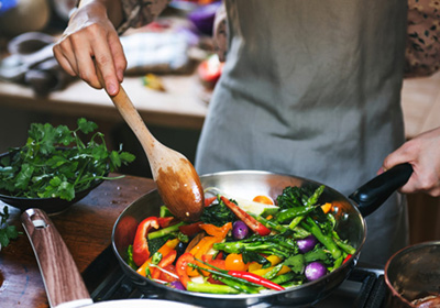 A person stir-frying some vegetables in a pan.