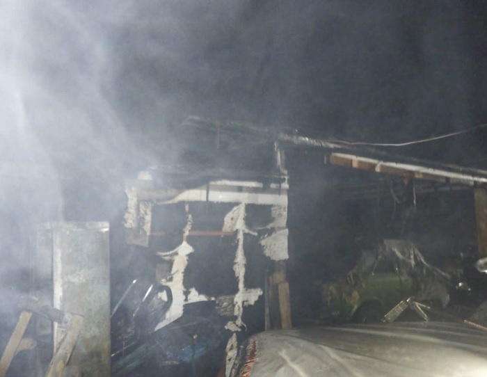 Burnt garage with green car in background