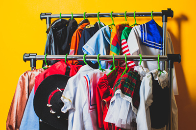 A variety of fancy dress costumes hanging on a clothes rail.