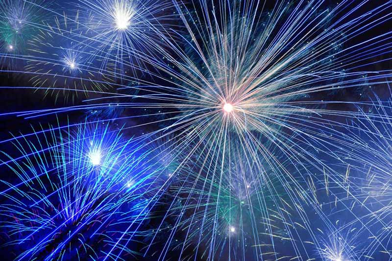 Blue, green and white fireworks in the night sky.