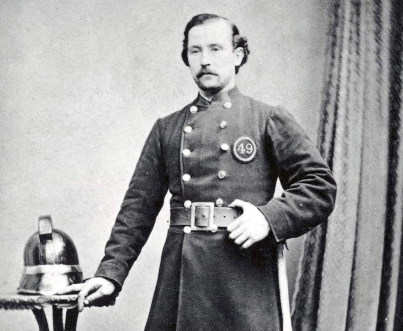 A firefighter from the London Fire Engine Establishment proudly wearing his uniform whilst a formal studio portrait was taken