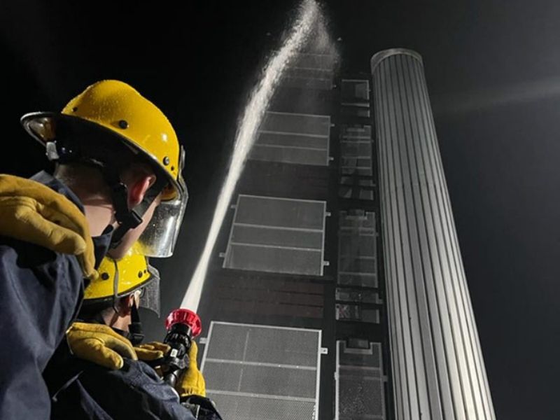 Cadets squirting a hose at a drill tower.