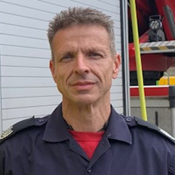 Carl Cooper standing in front of a fire engine.