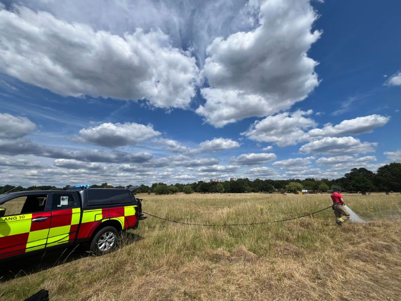 Firefighter using the hose attached to a wildfire vehicle in Richmond Park