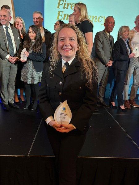 Lucy Macleod at an award ceremony holding an award in front of a crowd of people