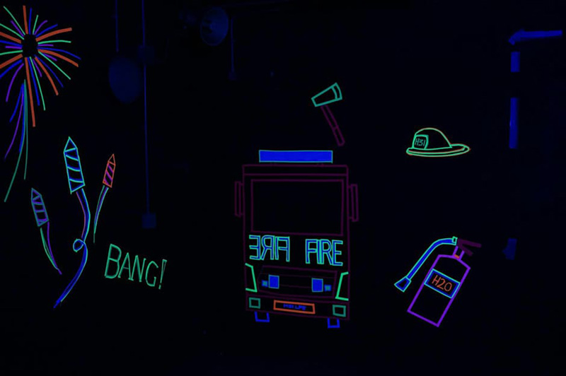 Glow in the dark decorations of a fire engine, axe, fire helmet, fire extinguisher and some fireworks.