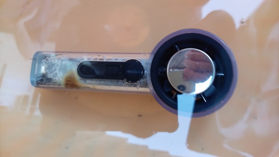 A handheld fan on a table with a small scorch mark on the handle