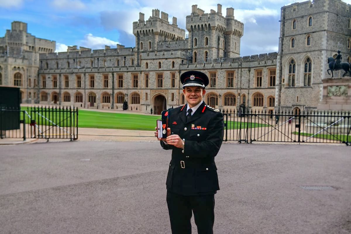 Commissioner Jonathan Smith holding his King Fire Service medal outside Windsor Castle
