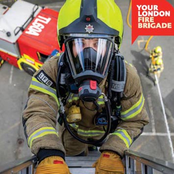 A firefighter at the top of a ladder.