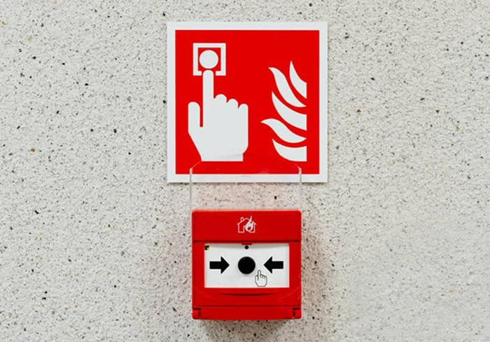 A fire call point with a sign above it