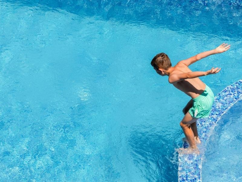 Boy about to jump into a swimming pool.