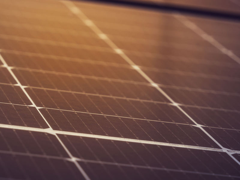 Solar panels with an orange glow from the sun reflected on the surface.