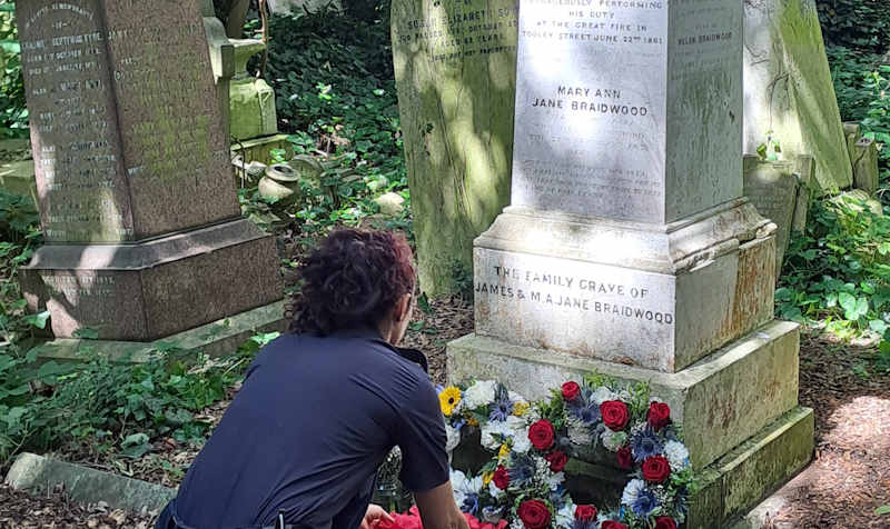 A firefighter from Stoke Newington laying a wreath at Braidwood's grave in 2024