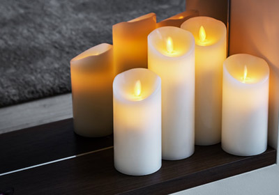 Four battery-operated pillar candles sitting in a fireplace.