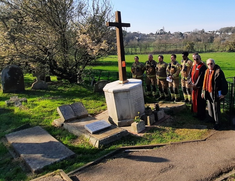 Firefighters stand around a large cross in a graveyard