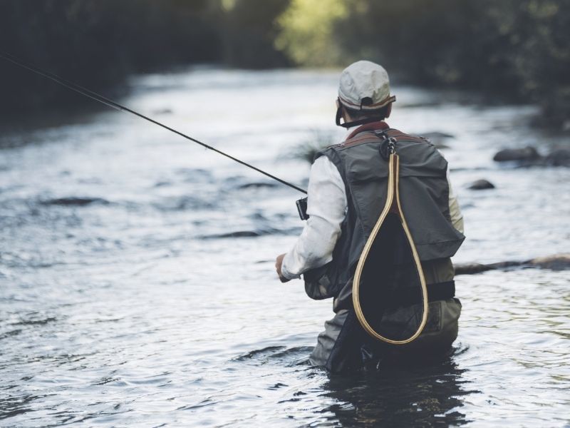 Person standing in the middle of a river angling.