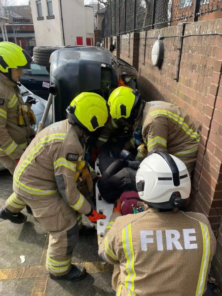 Four firefighters practising a rescue from a road traffic collision.