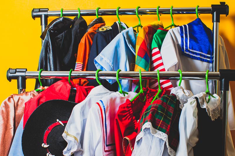A variety of fancy dress costumes hanging on a clothes rail.